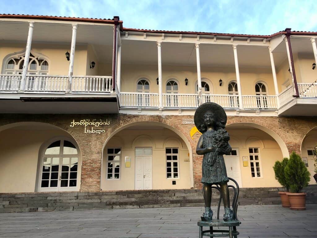 The famous wedding house of Sighnaghi with a statue of a little girl in front
