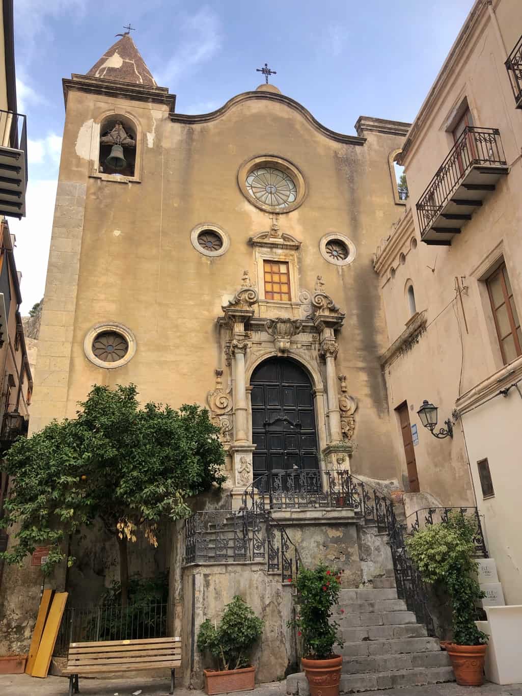 The baroque facade of Saint Stephen Protomartyr with staircase and trees. 