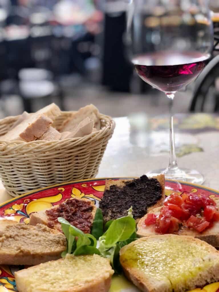 A glass of red wine, bread and a plate of mixed bruschette with olive oil, truffles and tomatoes - delicious. 