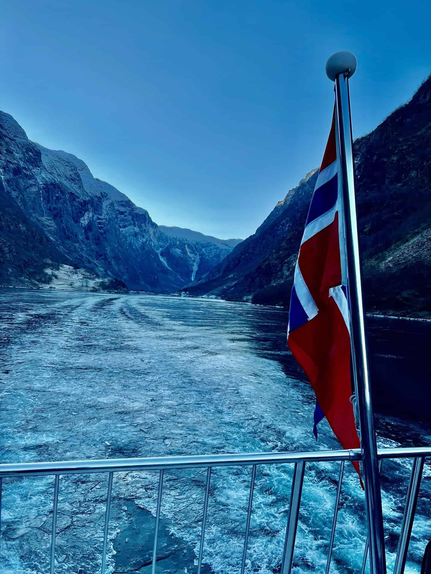 picture of the ice waters of fjord from back of ship with flag