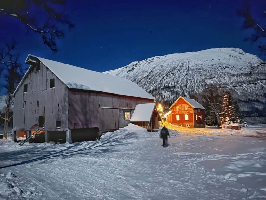 A house and shed in a snowy field with a mountain in the background. This is where we waiting to see the Northern Lights.  