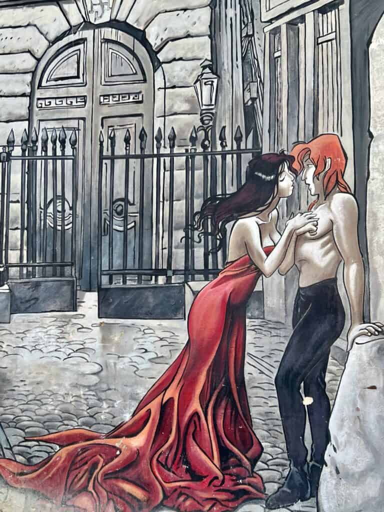 A cartoon mural with a girl in a long red dress trying to kiss a bare chested man with orange hair