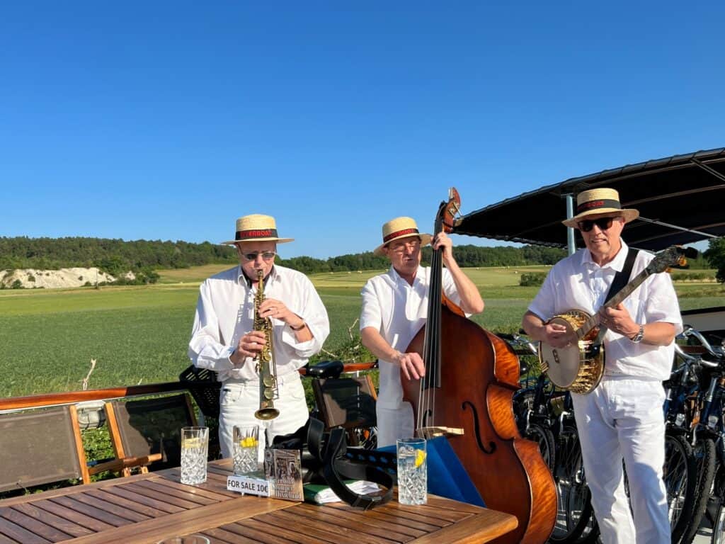 Three musicians wearing boaters. One playing saxophone, one on double bass and one on banjo on our luxury barge cruise in Burgundy 