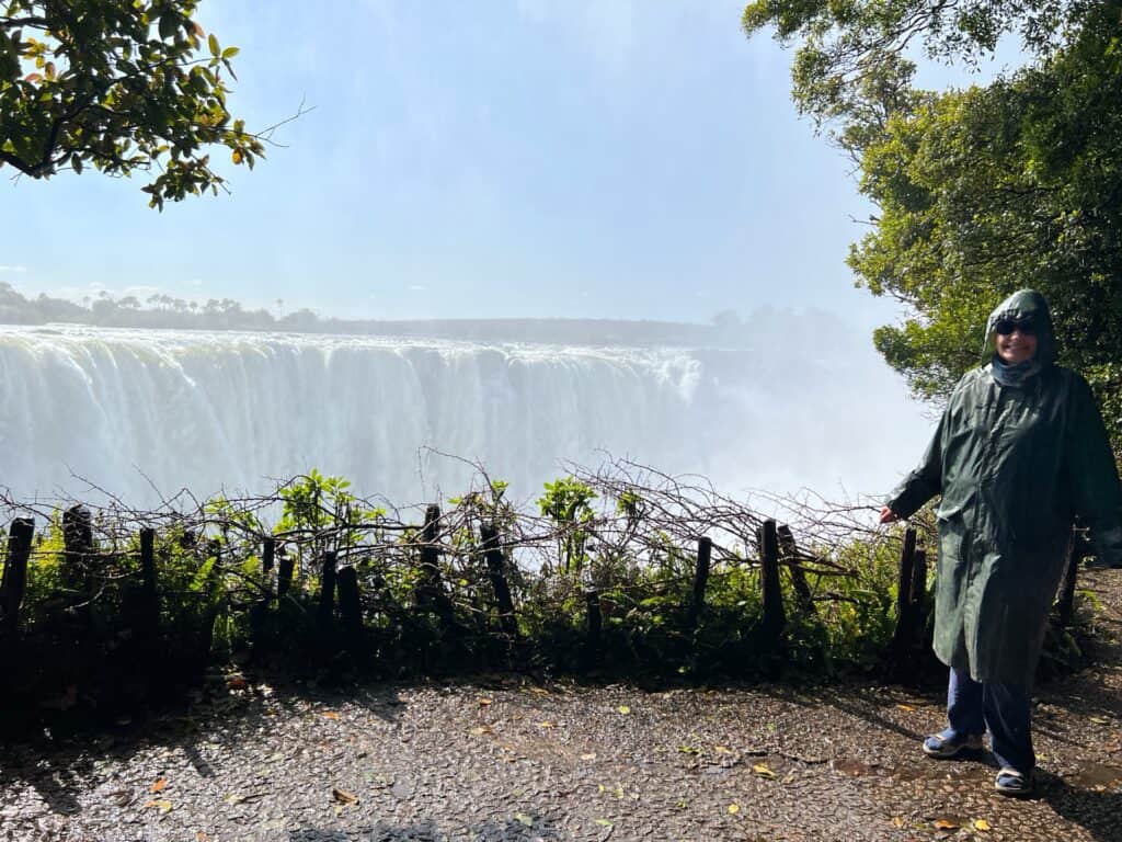 Lady in green raincoat in front of the main falls on day trip from Kasane to Victoria Falls 
