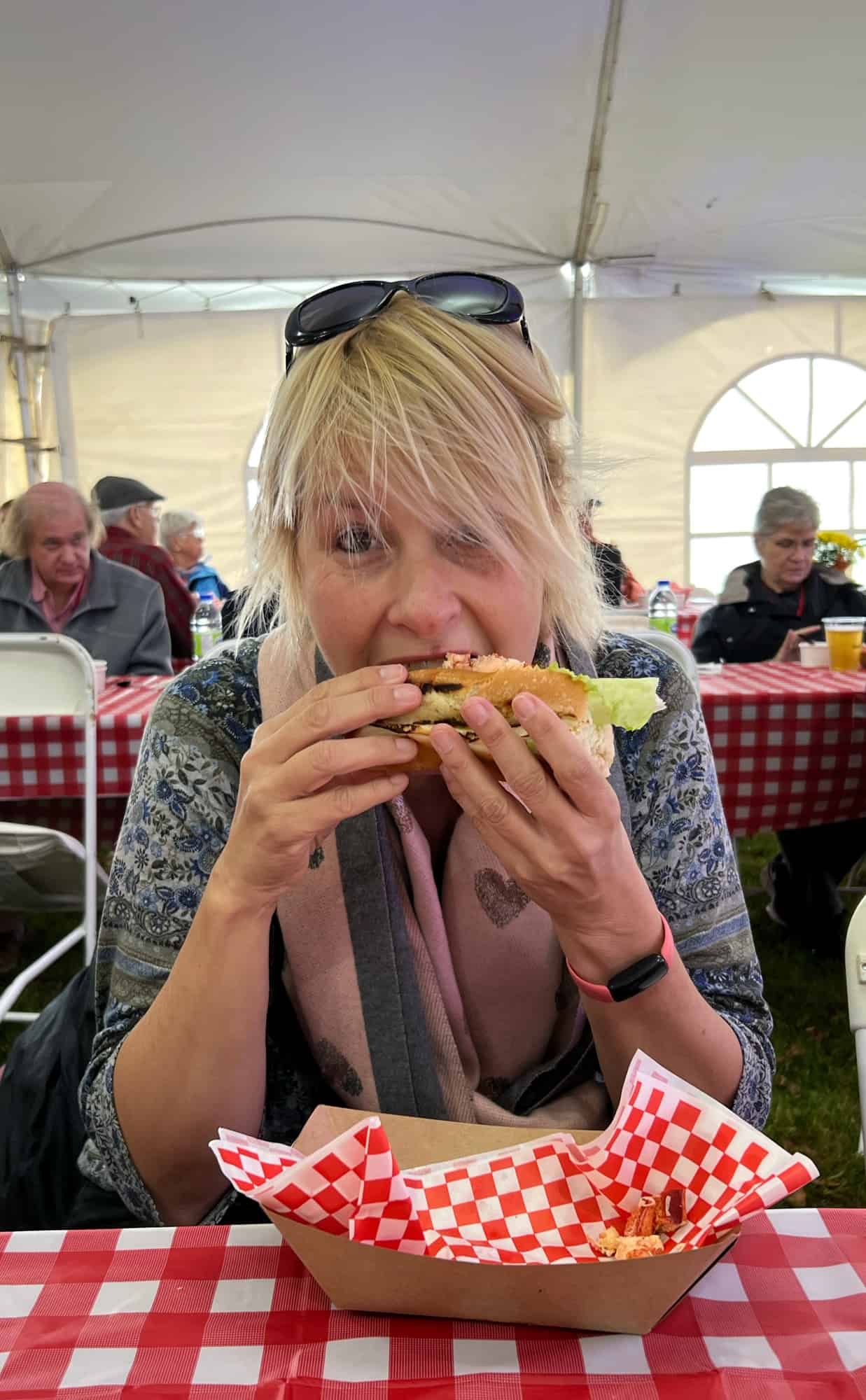 Lady wearing a pink scarf eating a lobster roll