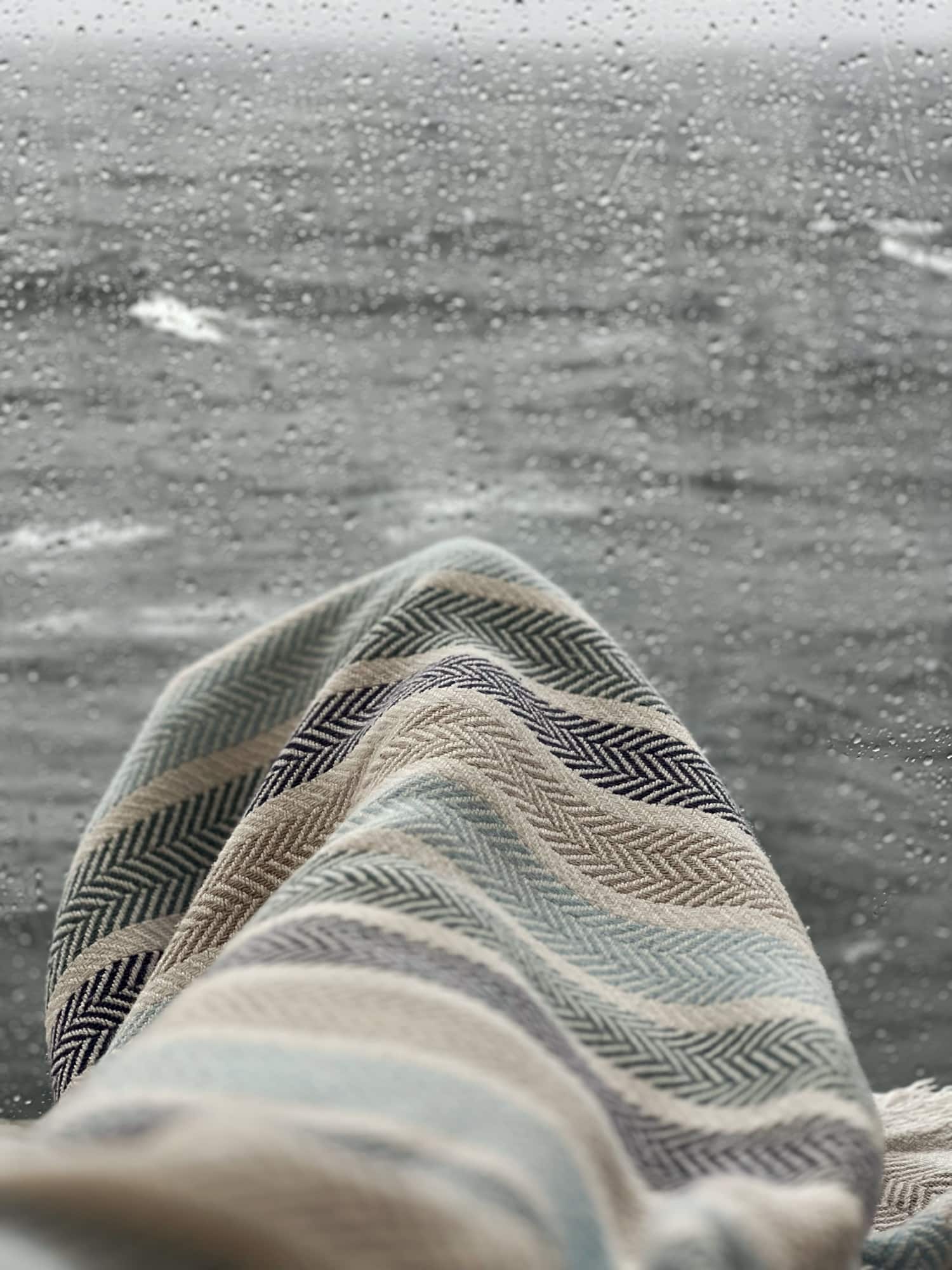 Snuggled under a blanket watching the rain on the ocean