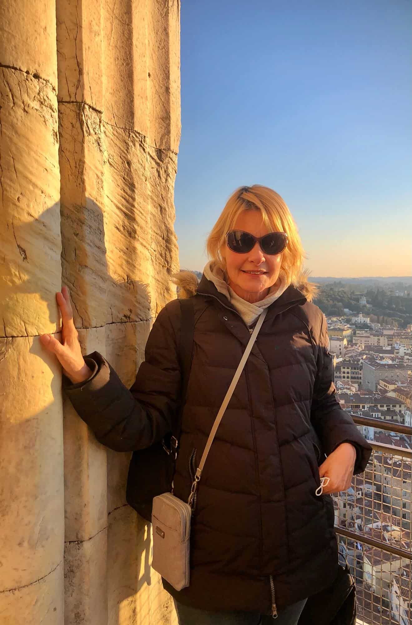 Blonde woman holding on to wall at top of the duomo in Florence