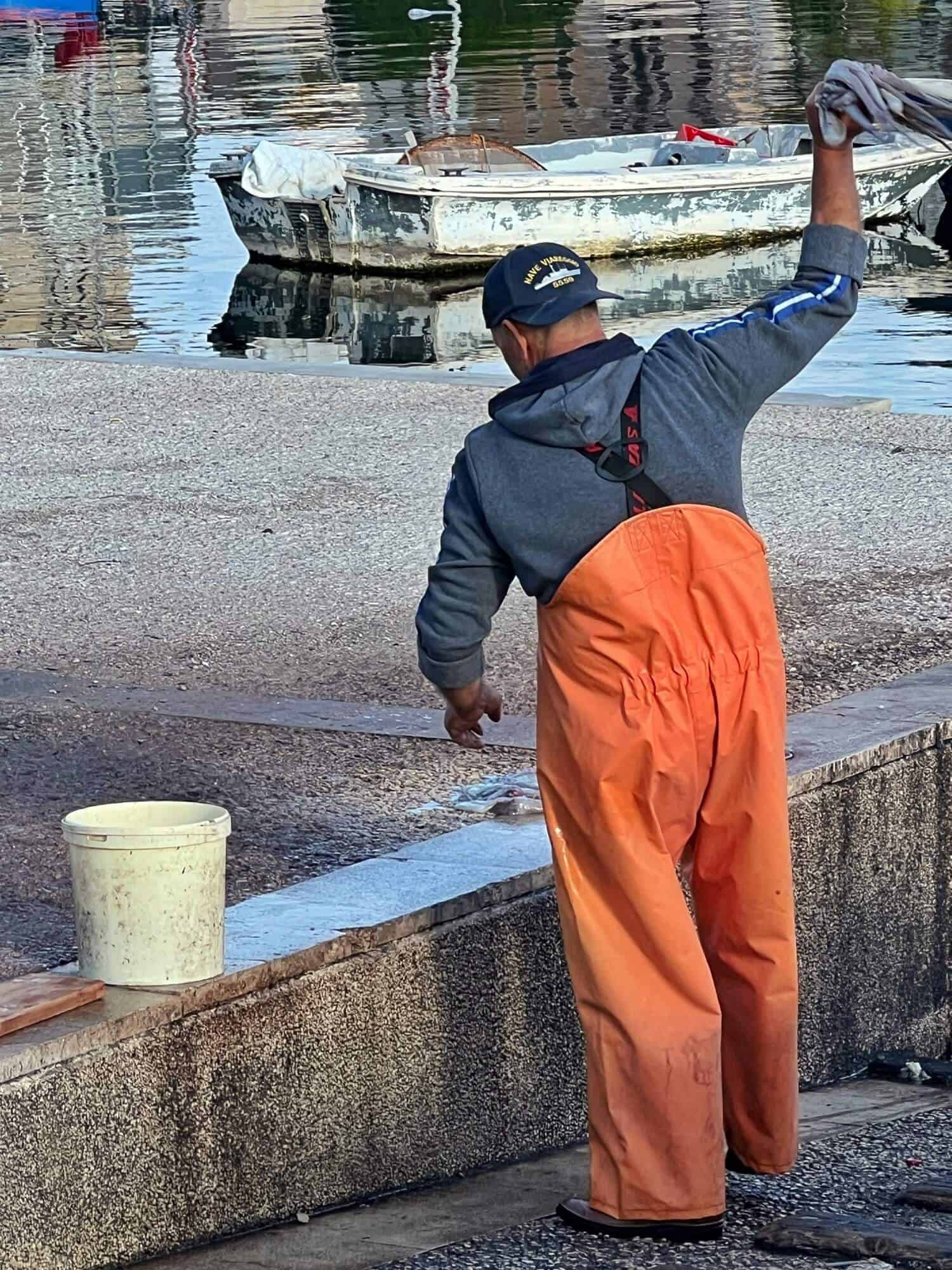 a fisherman wearing orange trousers and baseball cap with octopus 