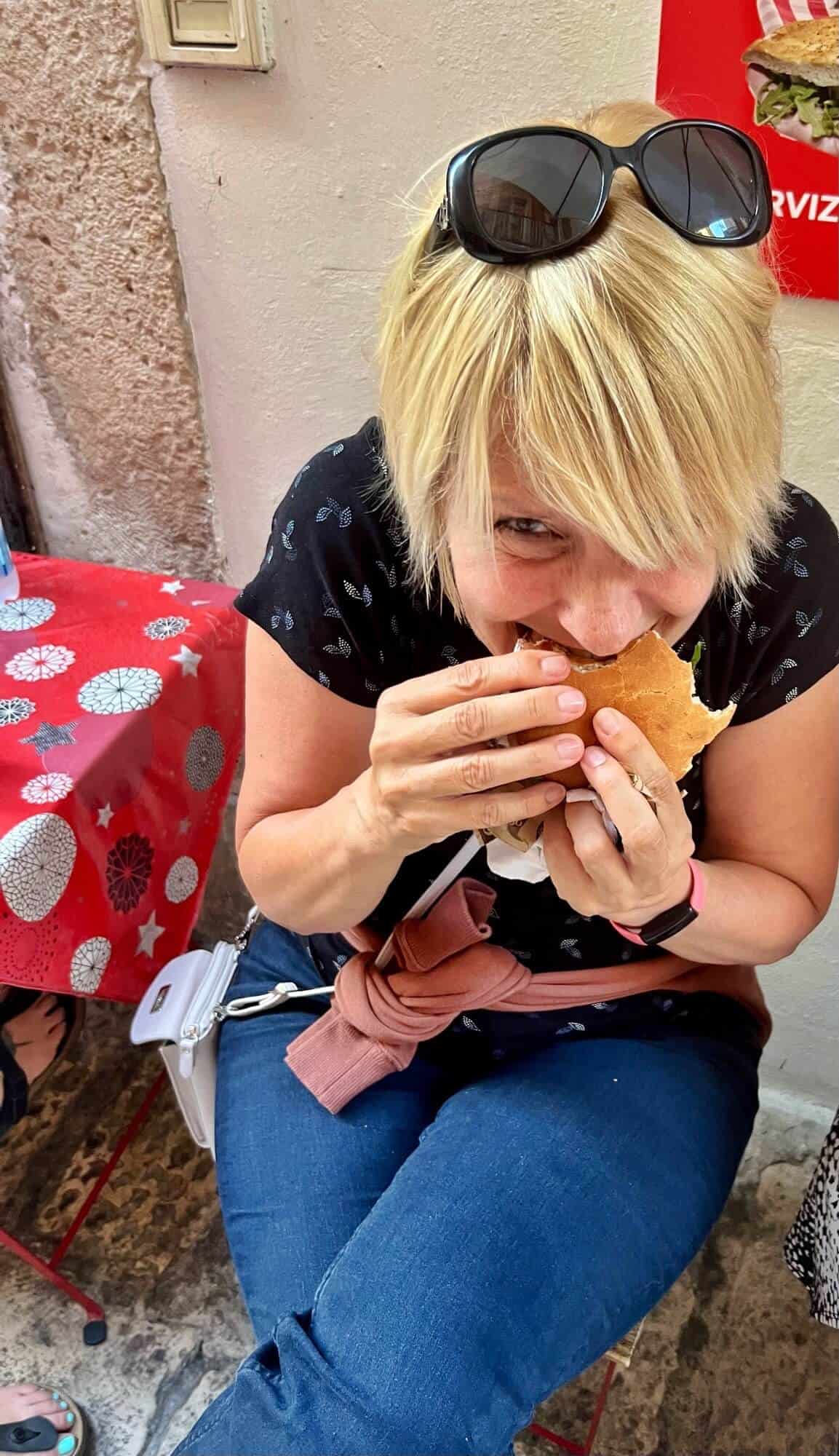 Lady tucking into an octopus sandwich on the streets of Bari