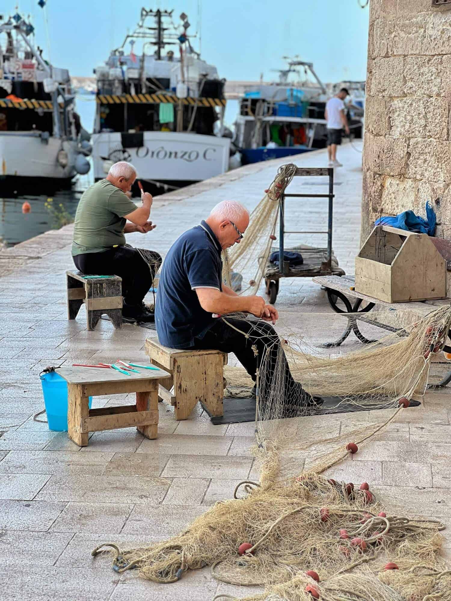 Two fisherman repairing the nets 