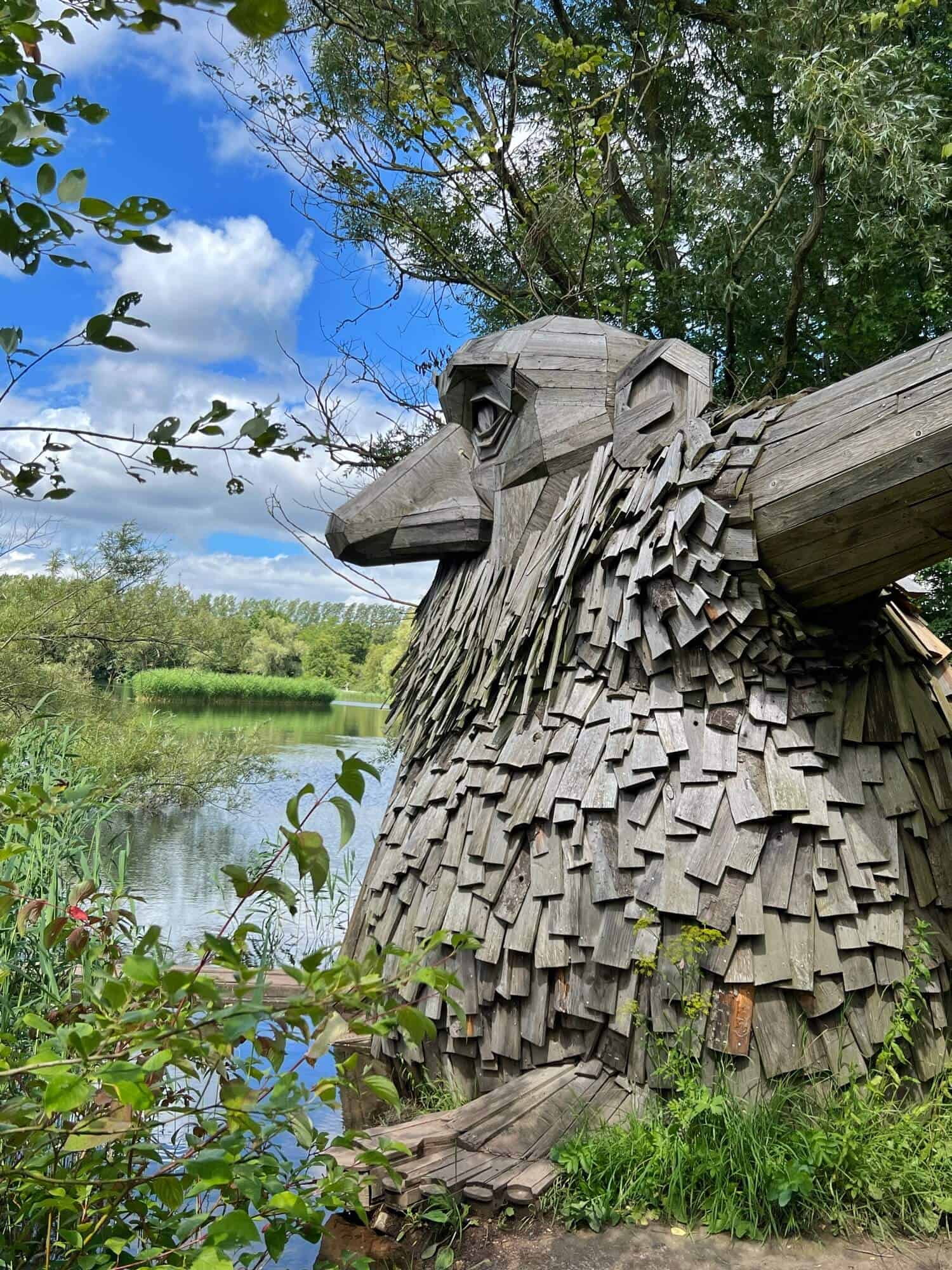 Side view of statue of Teddy Friendly next to a lake and tree 