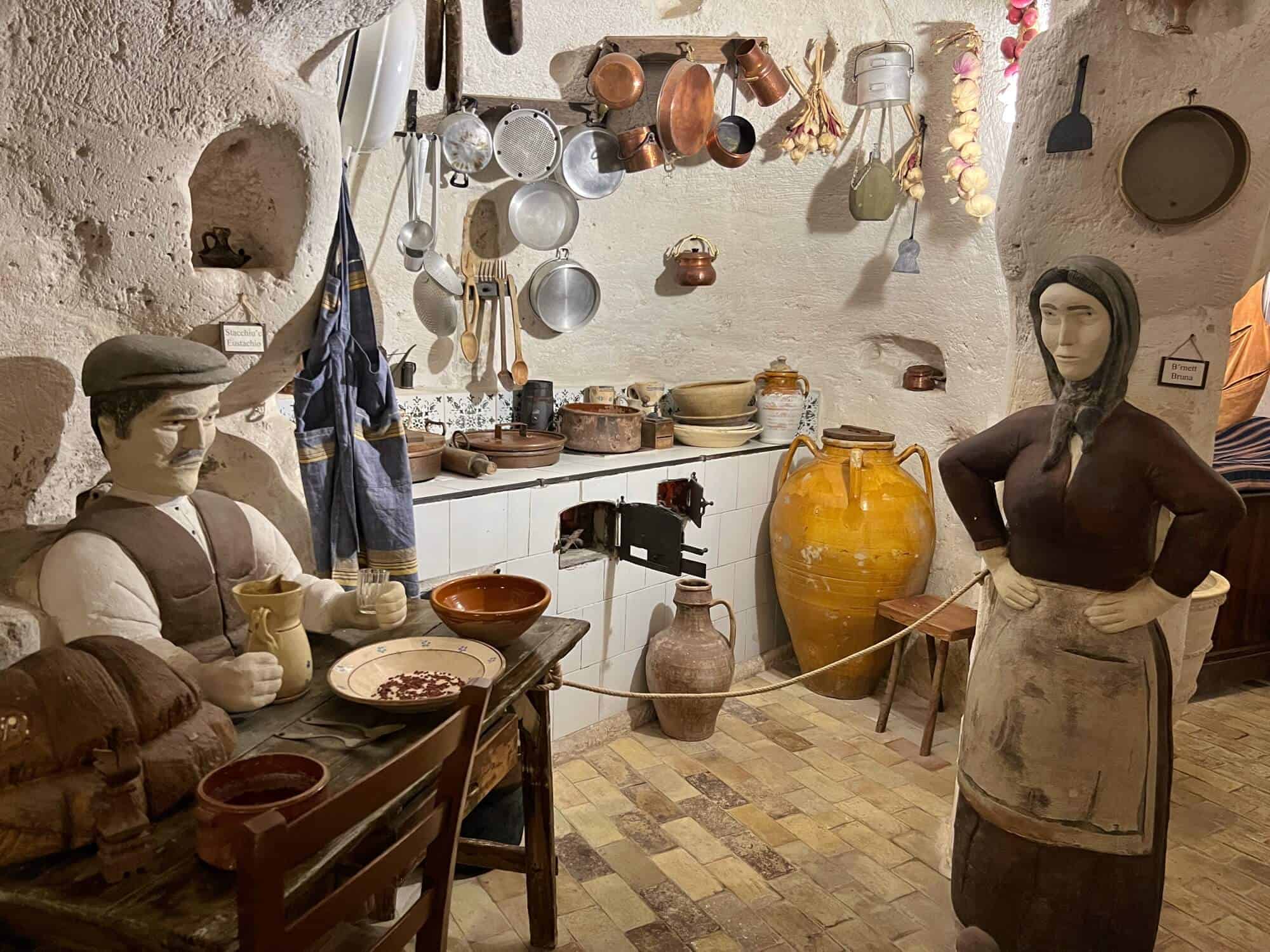 Inside a cave house in Matera. A model of a man sitting at a table eating in the kitchen. lady with hands on the hips. 