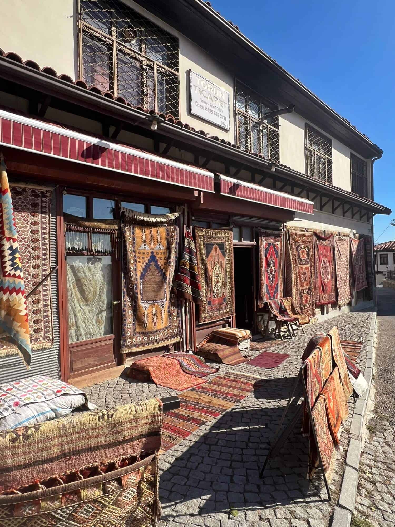 Rug shop with many Turkish rugs hanging or on the pavement 