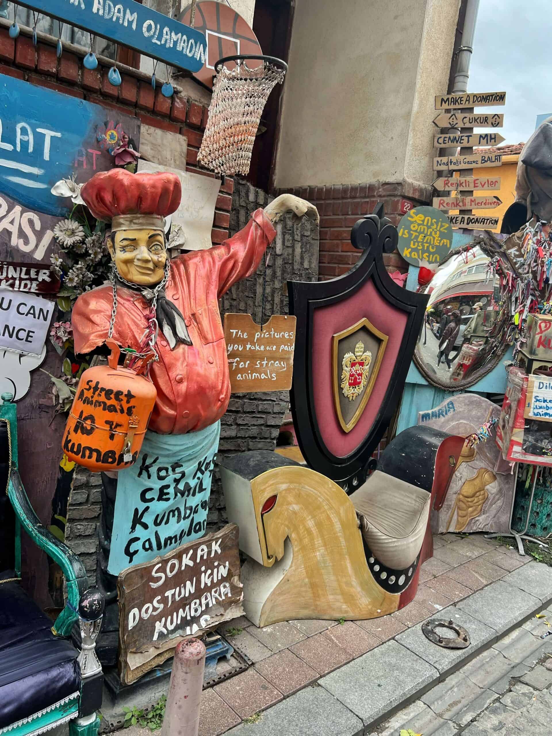 Colourful collection of antiques including a statue of a chef wearing a red hat and shirt 