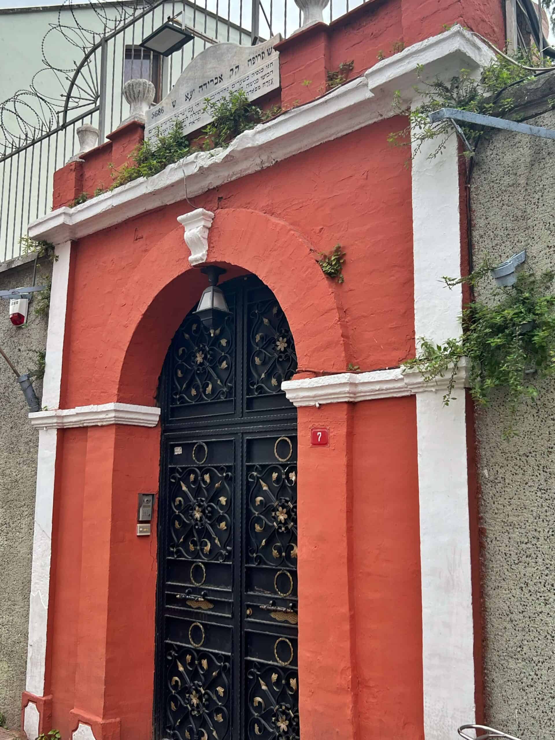 The closed black gate surrounded by a red wall of the Ahrida Synagogue 