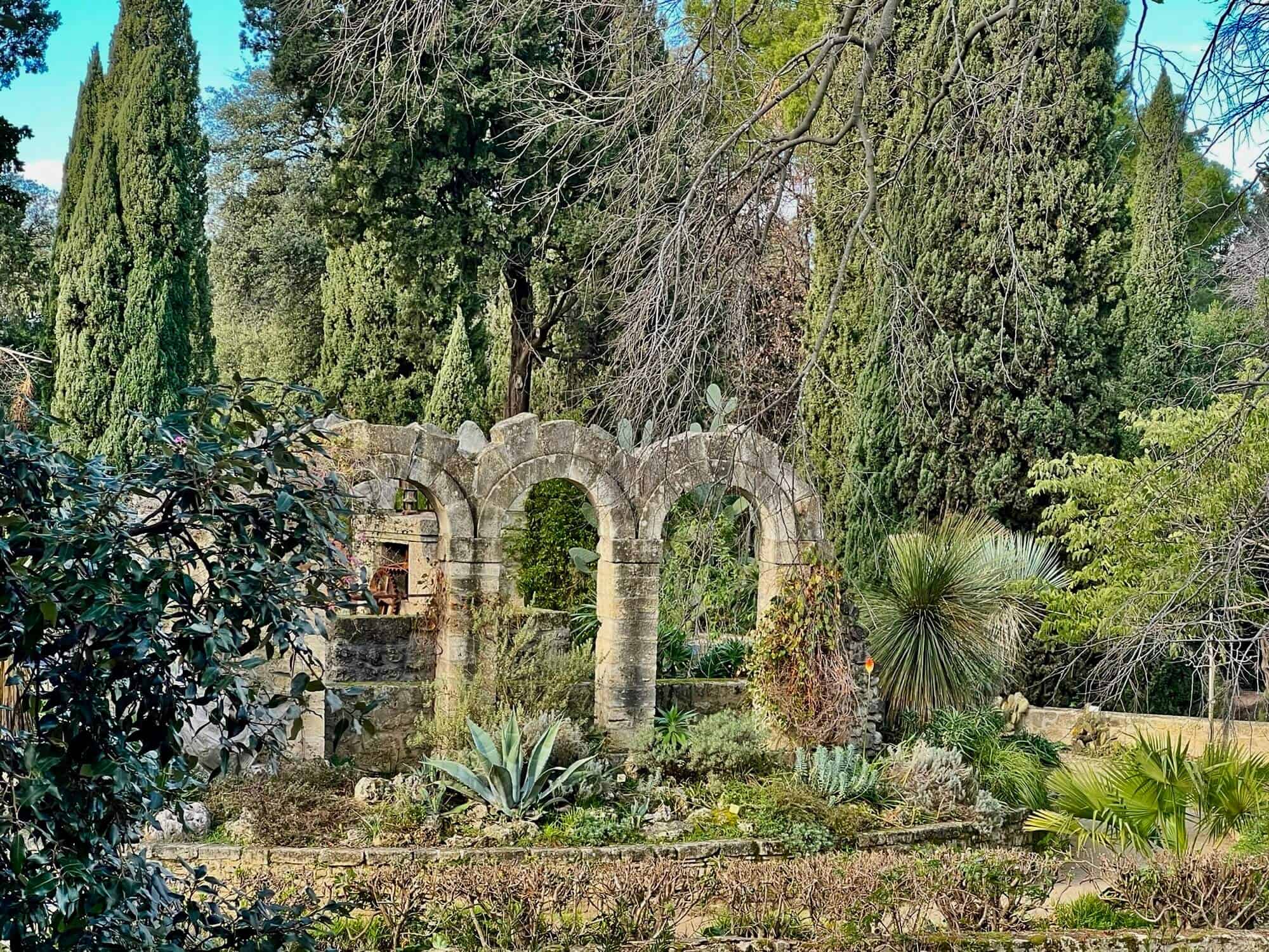 brick archways surrounded by trees and bushes at the Jardin Des Plantes