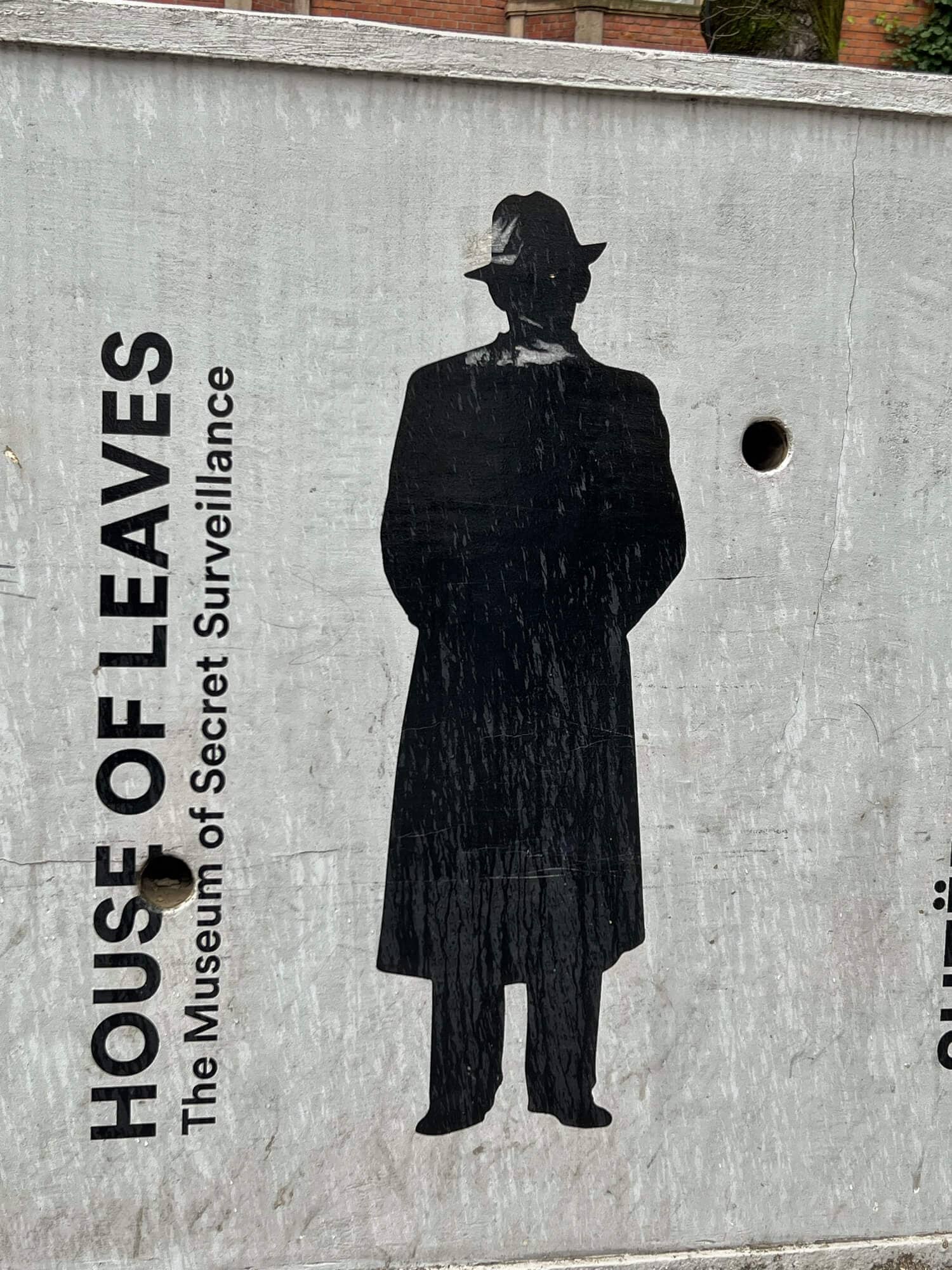 The sign with a man wearing dark clothes and a hat at the House of Leaves, Tirana 
