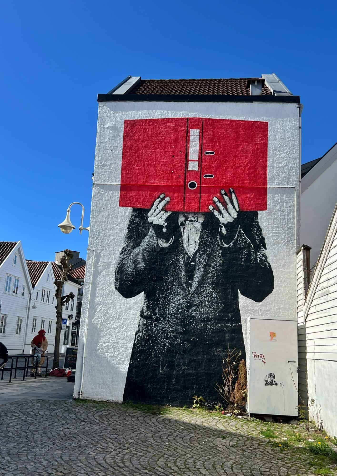 Street art depicting a man hiding his face behind a large red binder