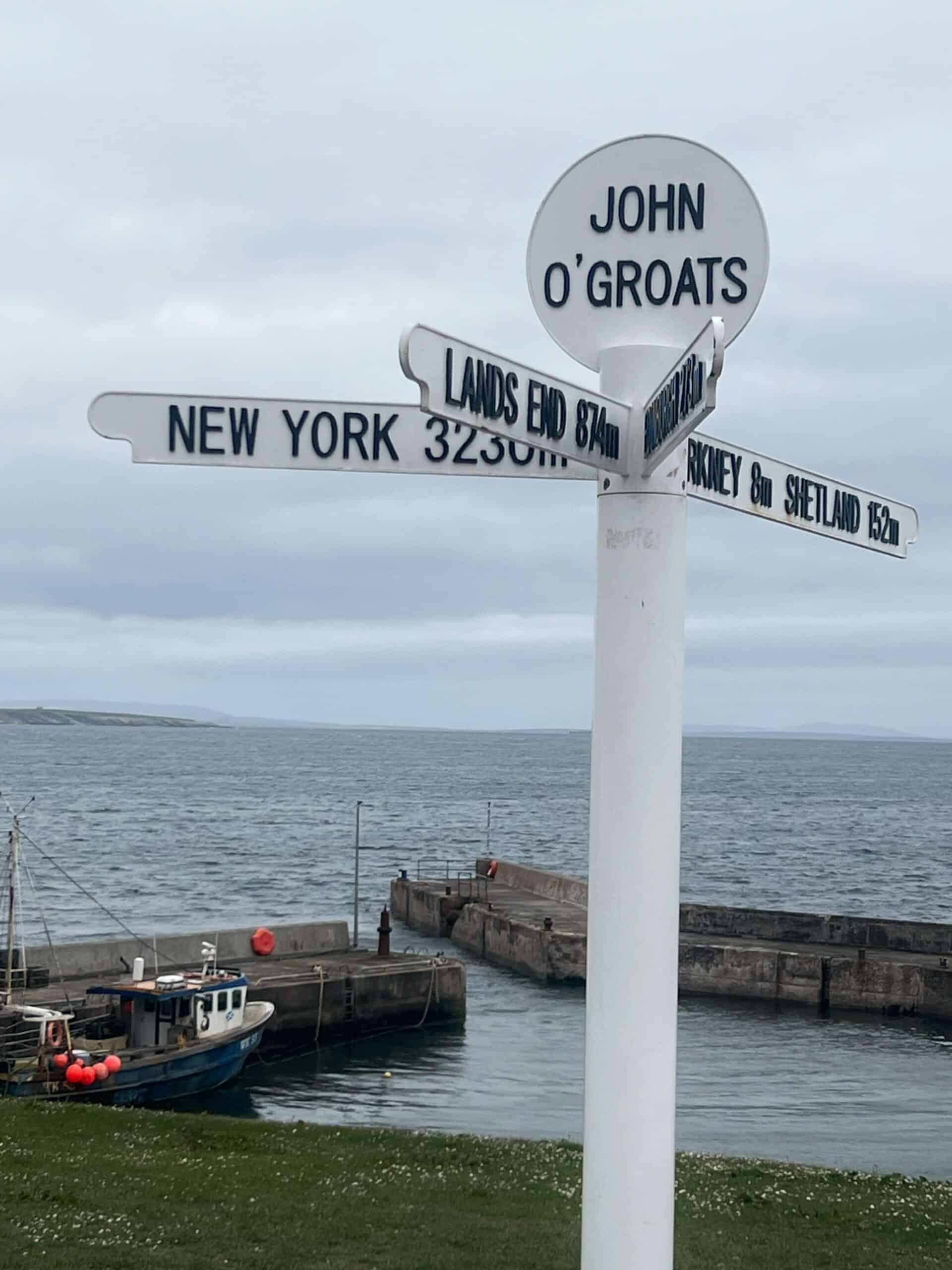 Sign at John O Groats showing 874miles to Lands End in front of the harbour