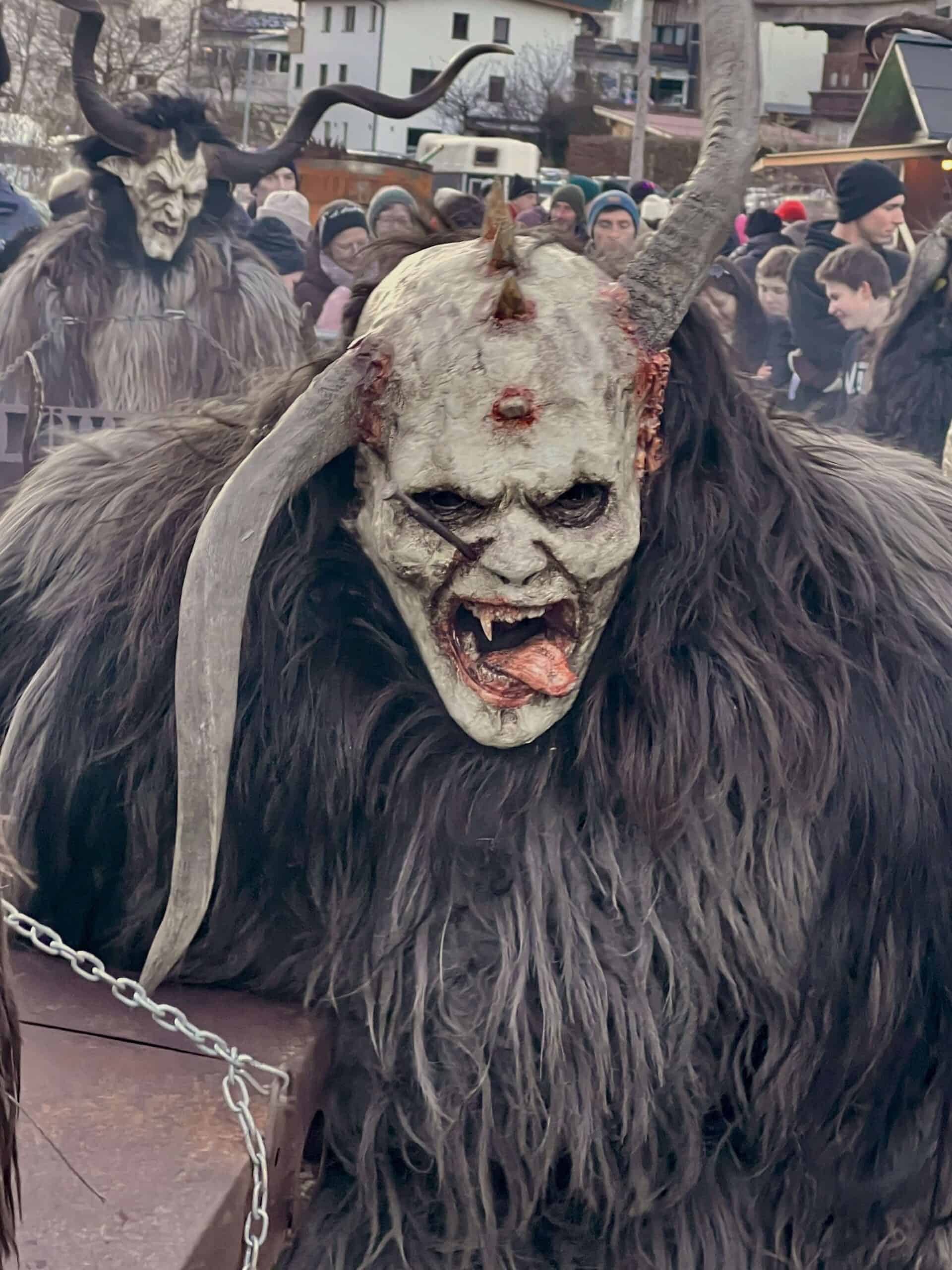 two Krampus with horns and Christmas crowds