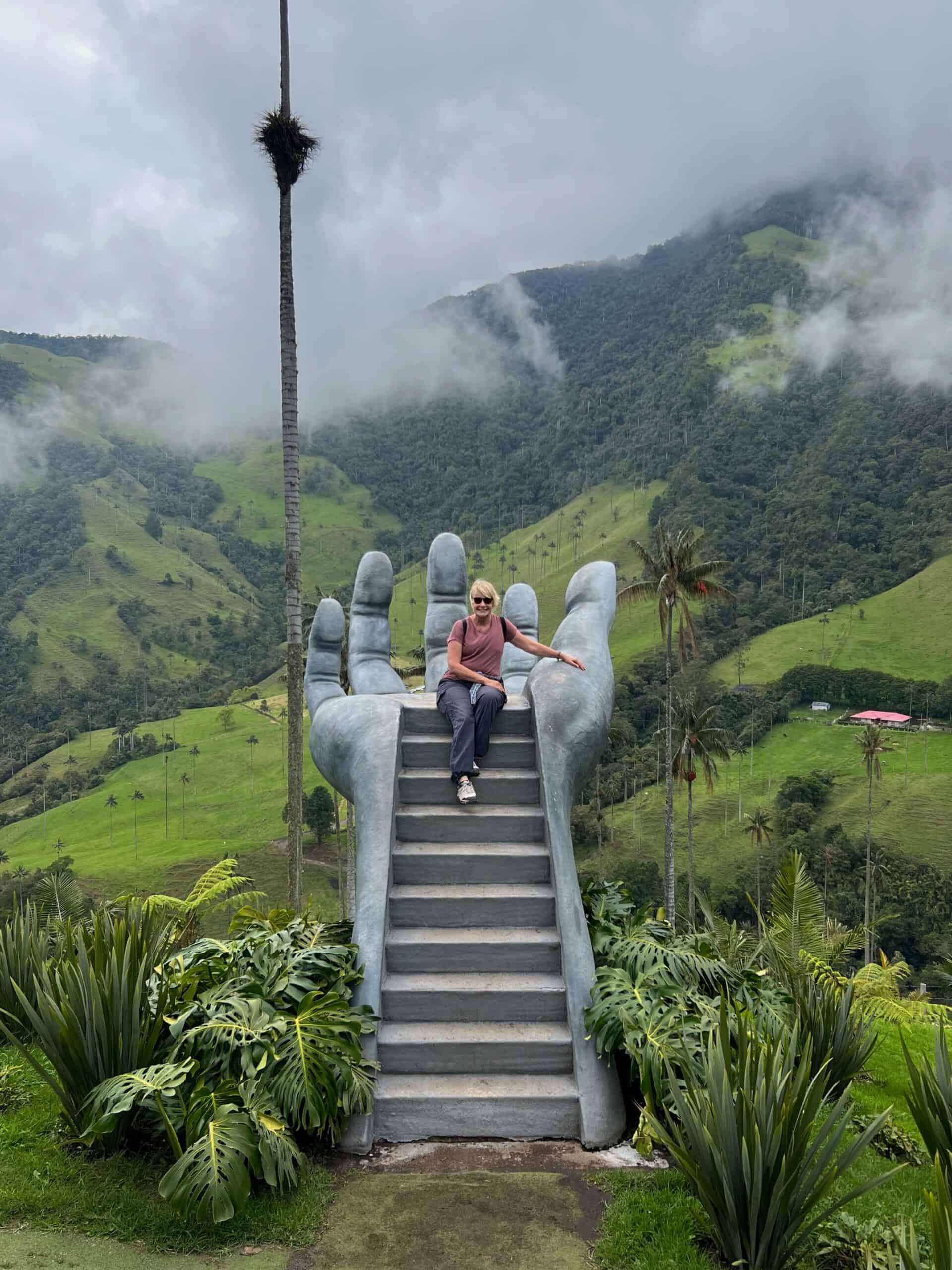 Lady sitting on a giant grey hand in the Cocora Valley 