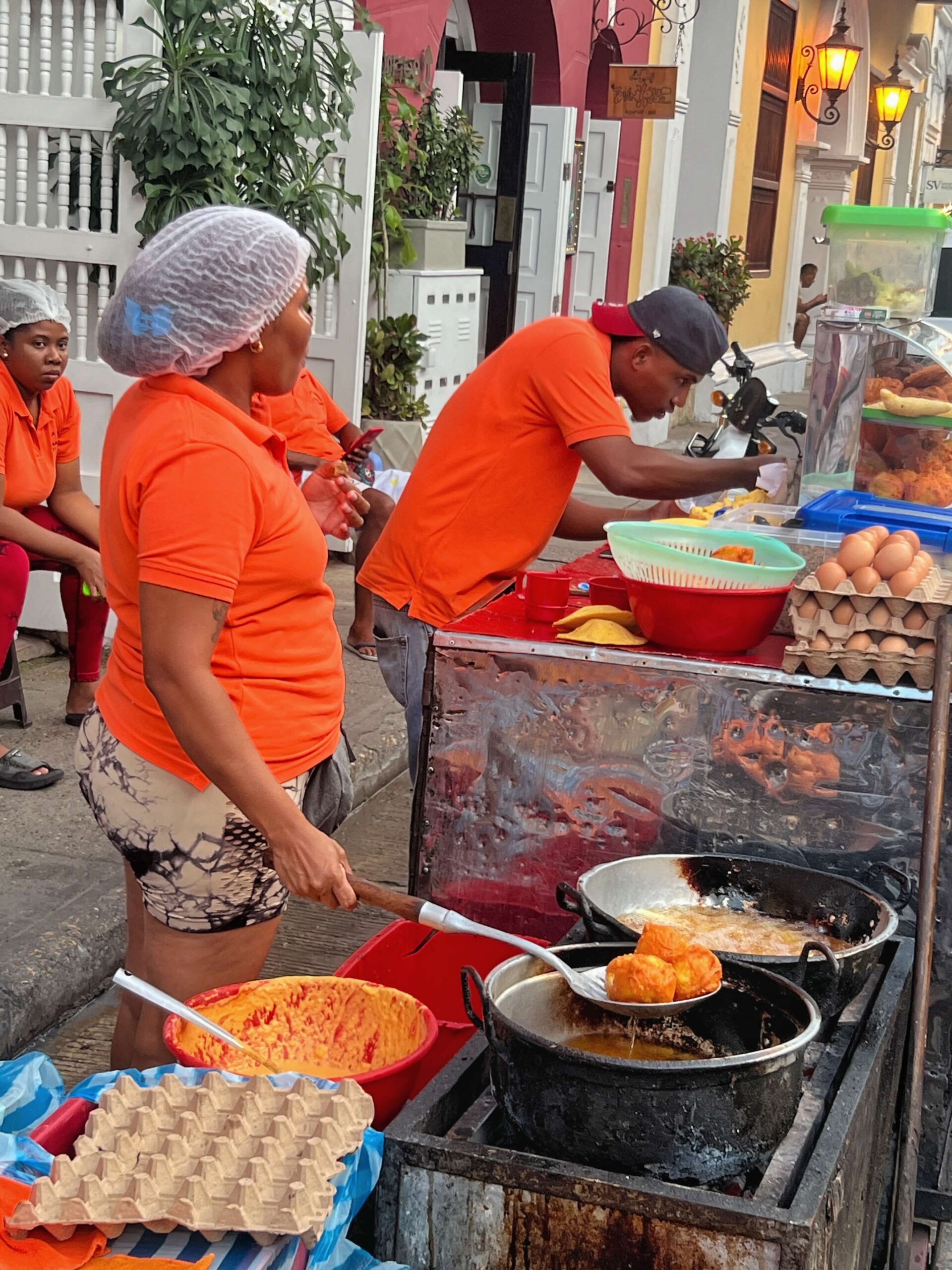 Street vendors in orange t-shirts cooking street food